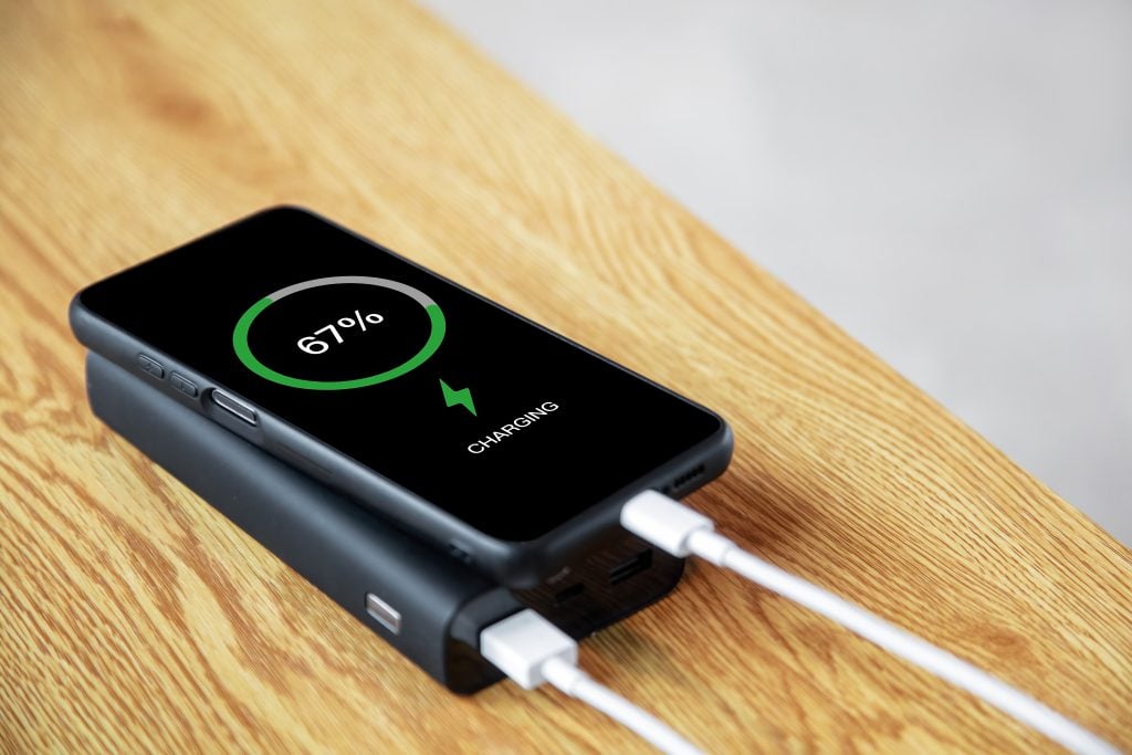 A mobile phone being charged using a power bank is on the table
